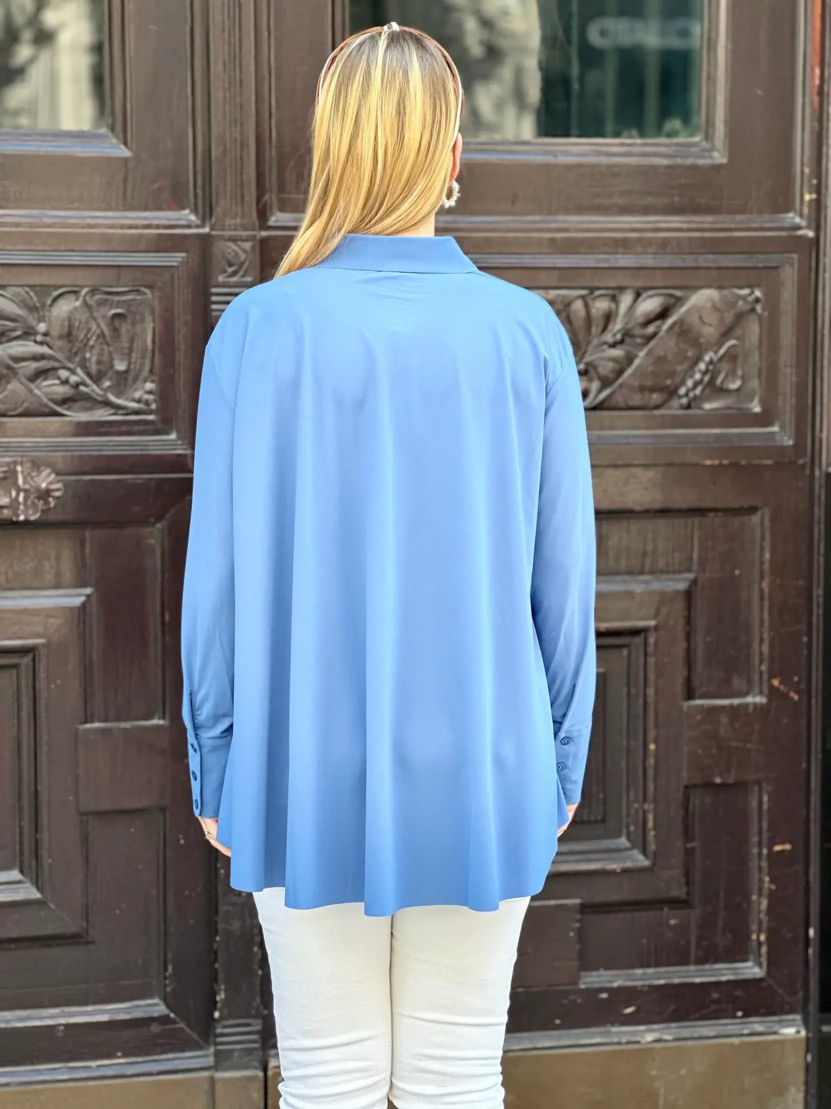 Rückansicht von junger Frau vor Hauseingang in der Bluse Milly in der Trendfarbe Jeansblau vom Hamburger Modelabel stegmann mode