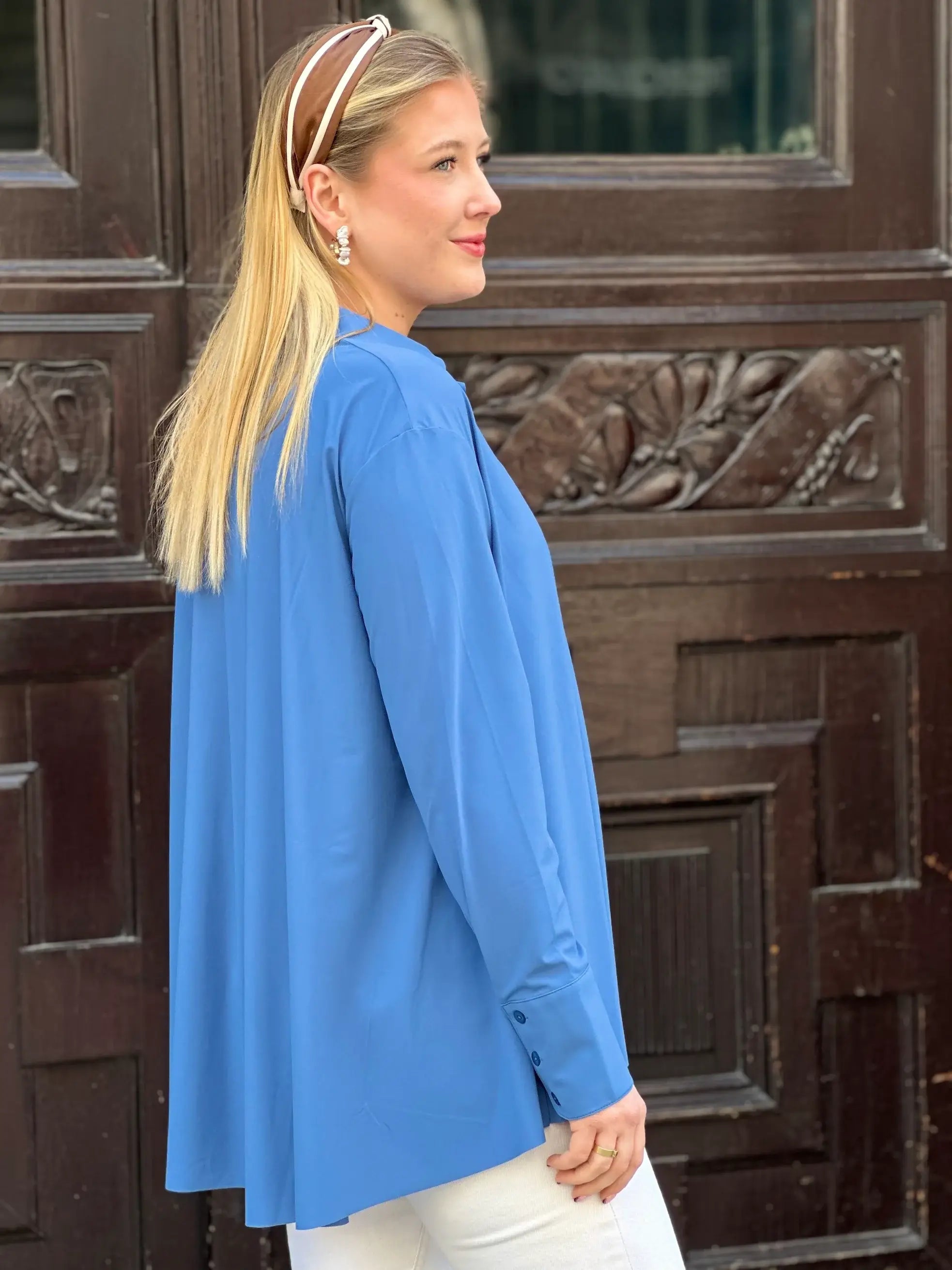 Seitliche Aufnahme von junger Frau vor Hauseingang in der Bluse Milly in der Trendfarbe Jeansblau vom Hamburger Modelabel stegmann mode