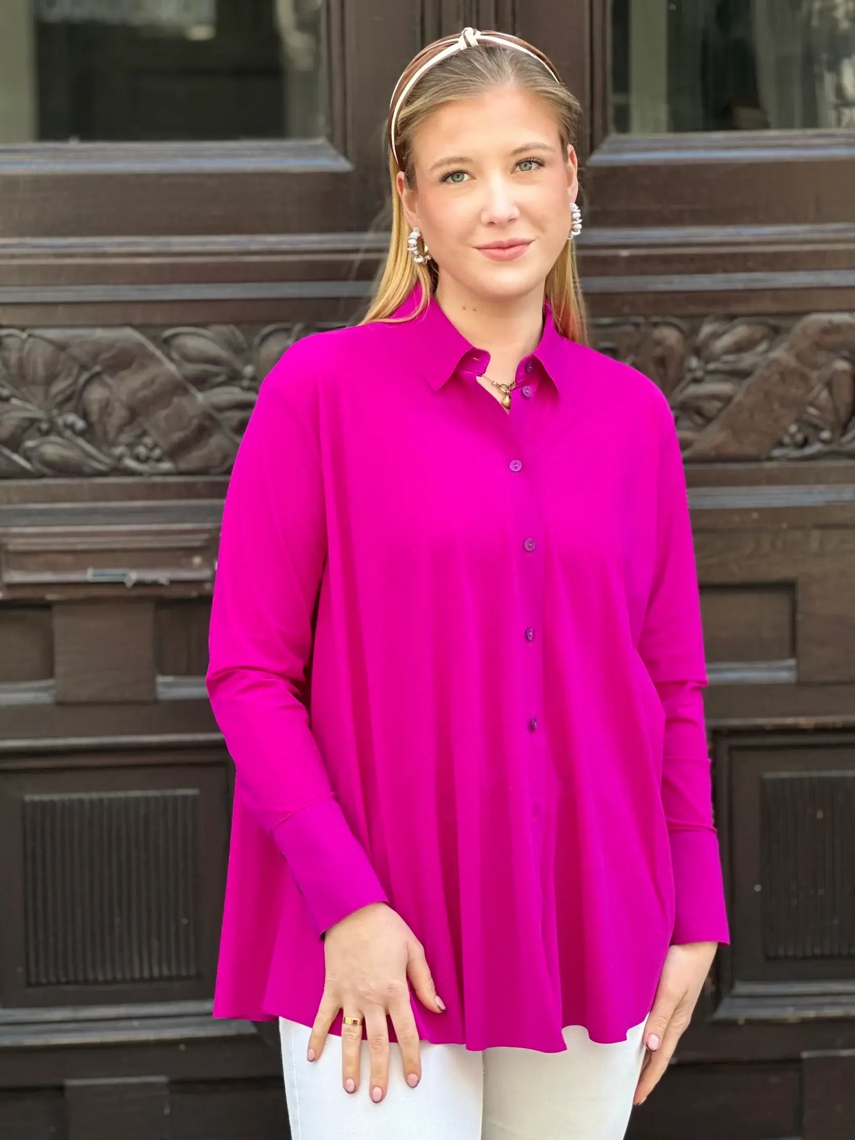 Junge Frau vor Hauseingang in der Bluse Milly in der Trendfarbe Magenta vom Hamburger Modelabel stegmann mode