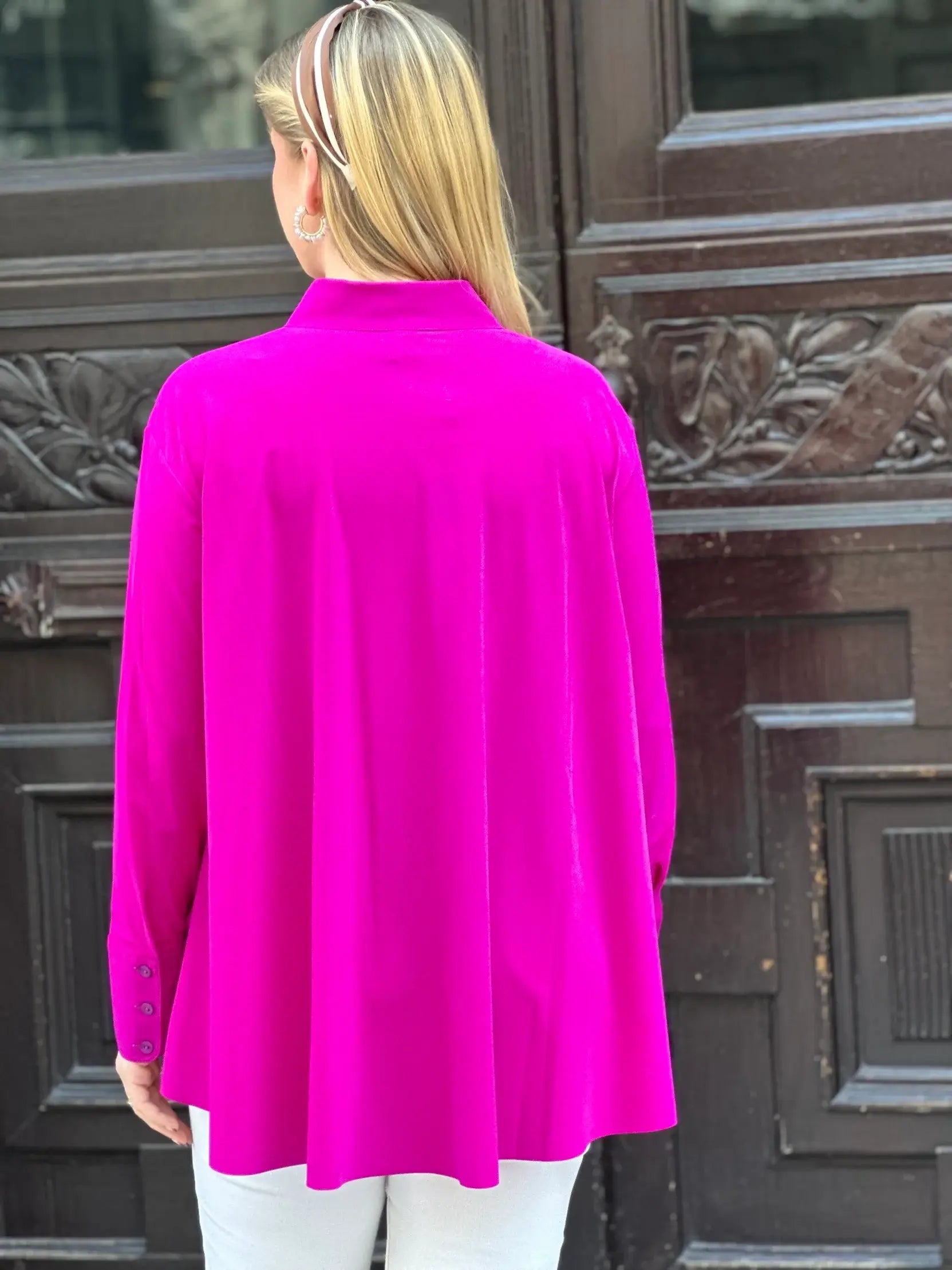 Rückansicht von junger Frau vor Hauseingang in der Bluse Milly in der Trendfarbe Magenta vom Hamburger Modelabel stegmann mode