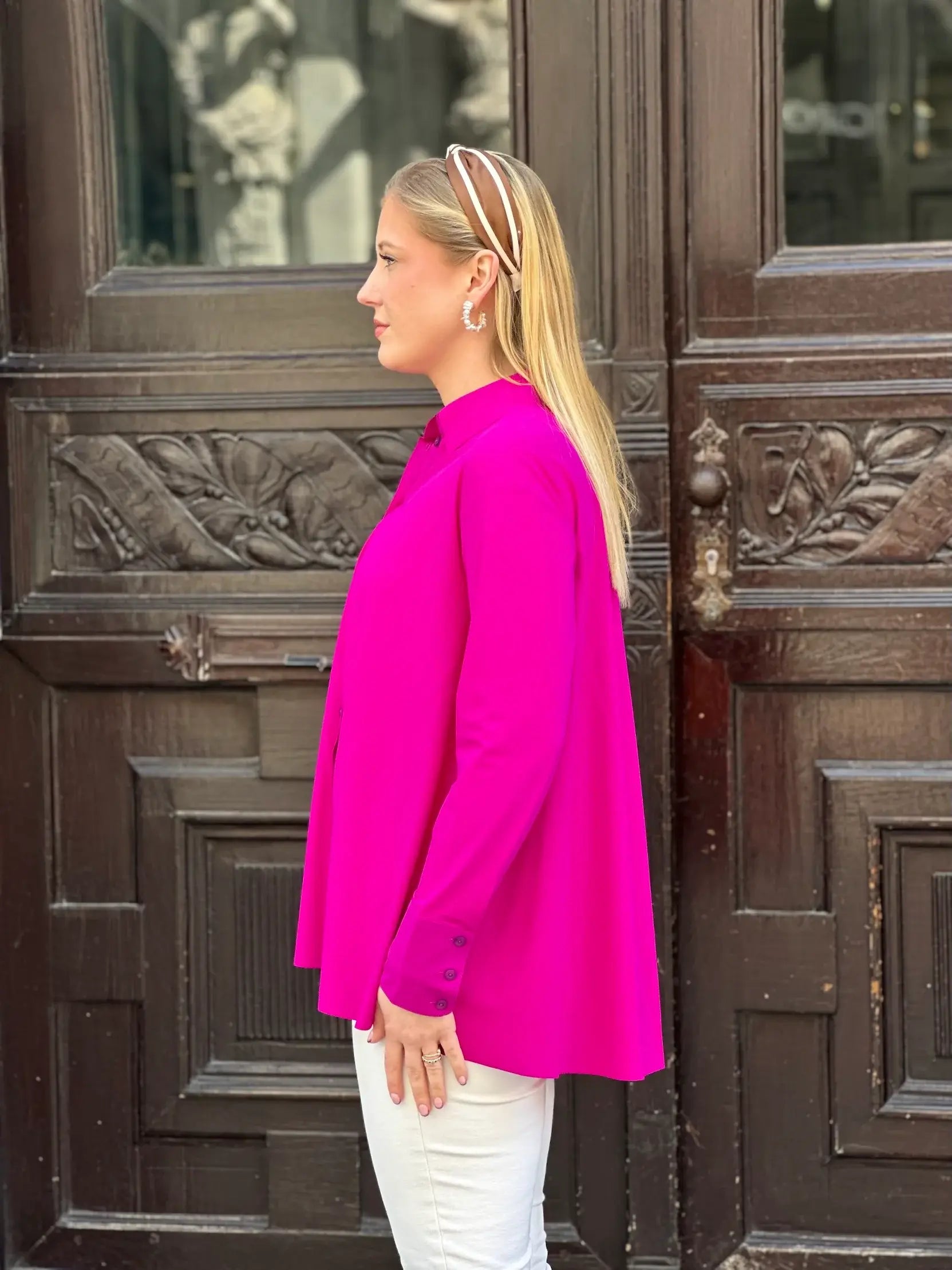Seitliche Aufnahme von junger Frau vor Hauseingang in der Bluse Milly in der Trendfarbe Magenta vom Hamburger Modelabel stegmann mode