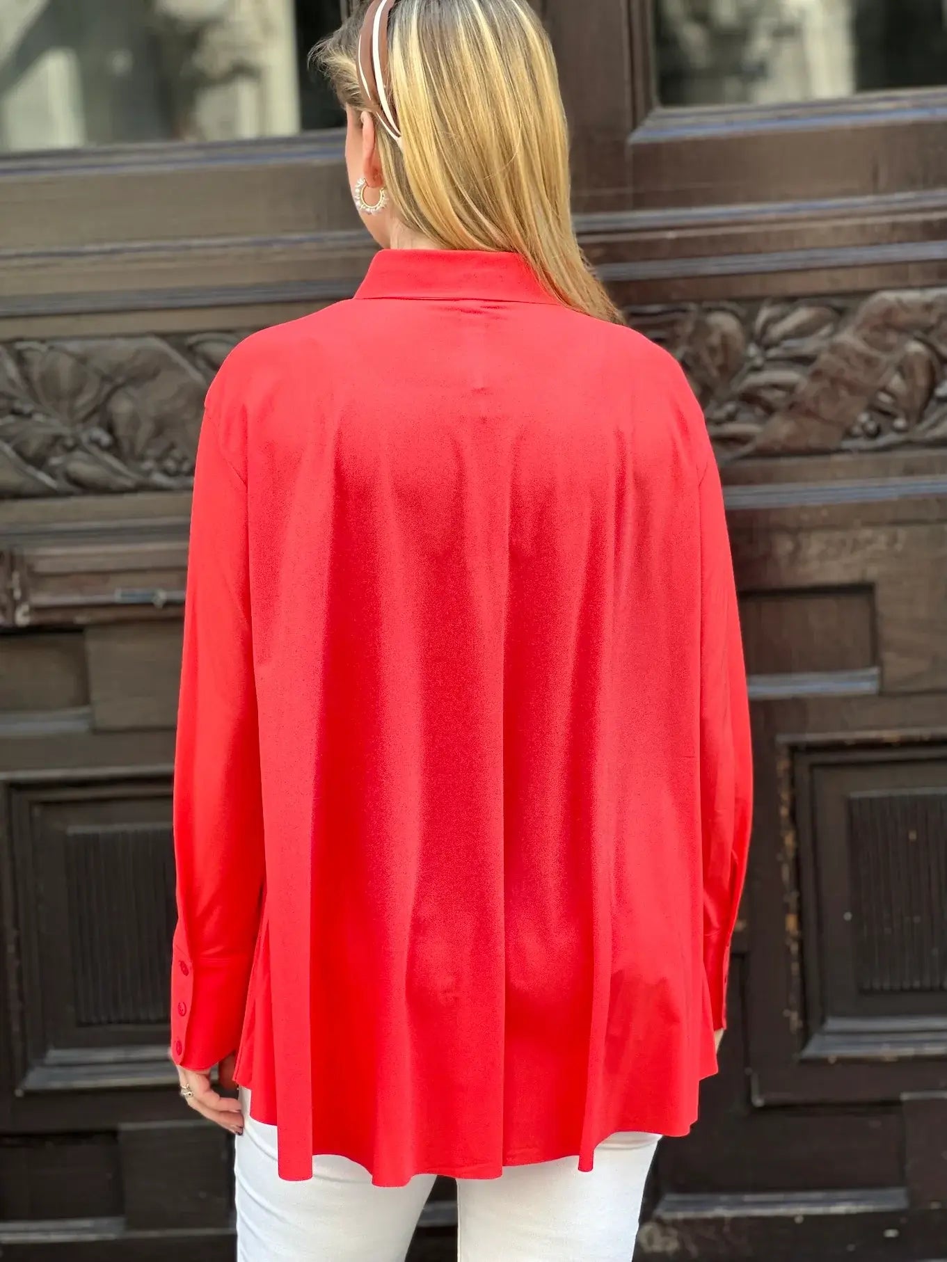 Rückansicht von junger Frau vor Hauseingang in der Bluse Milly in der Trendfarbe Orange vom Hamburger Modelabel stegmann mode