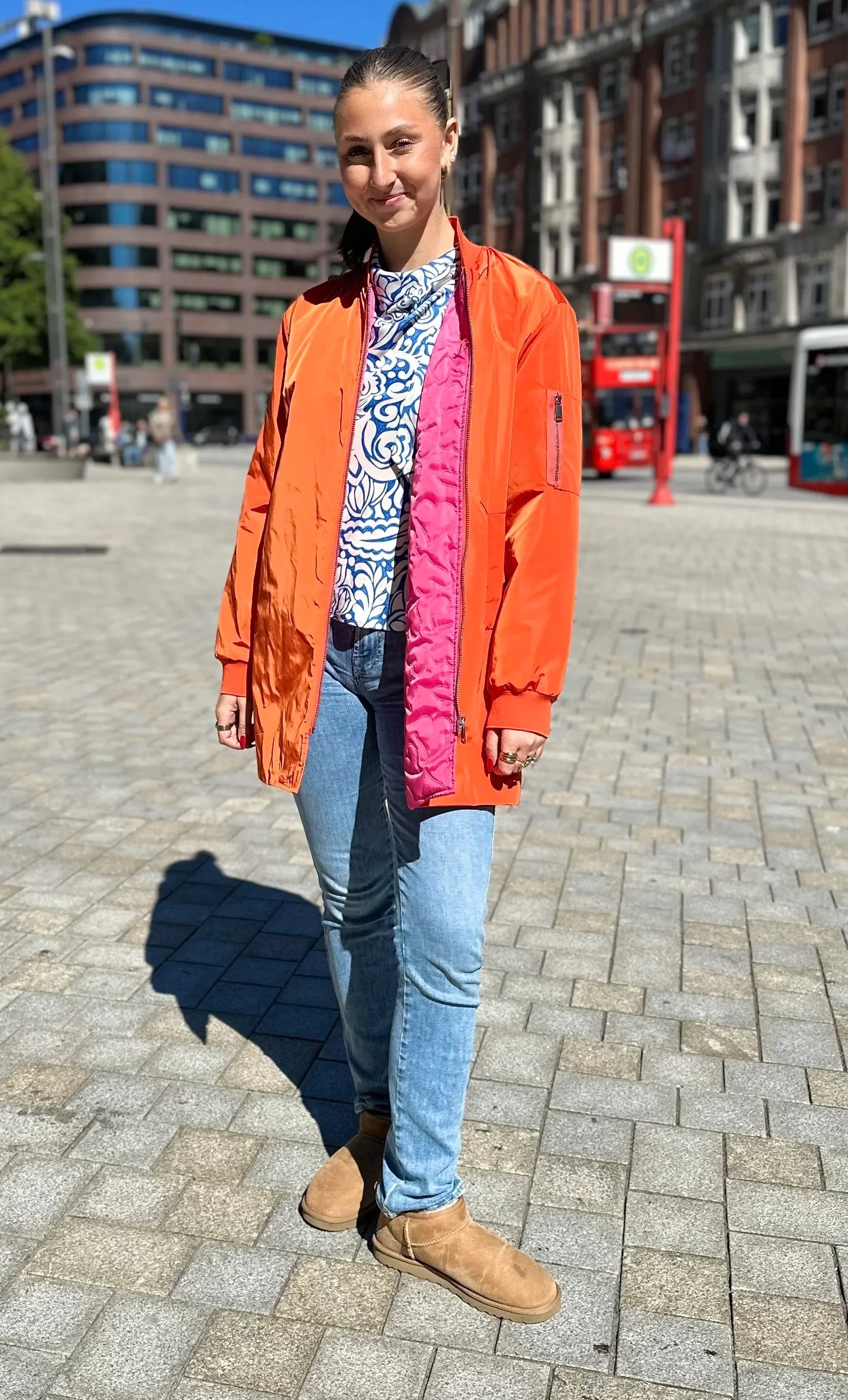 Frau im urbanen Umfeld im Kurzmantel Bomber in der Farbe Orange vom Hamburger Modelabel stegmann mode