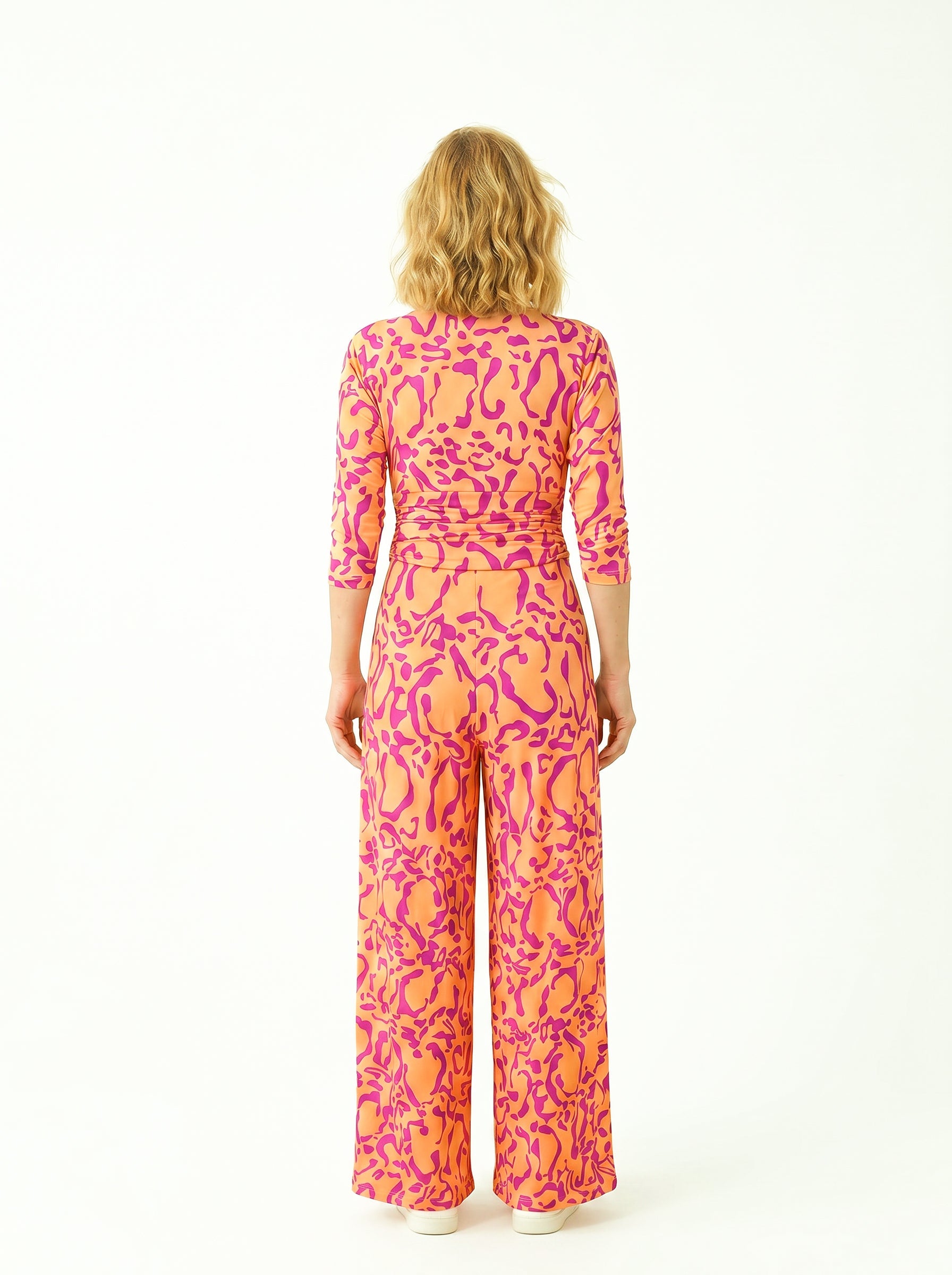 KI generiertes Modell von hinten im weißen Studio im Jumpsuit Romy Combi im Print Panthere Orange vom Hamburger Modelabel stegmann mode