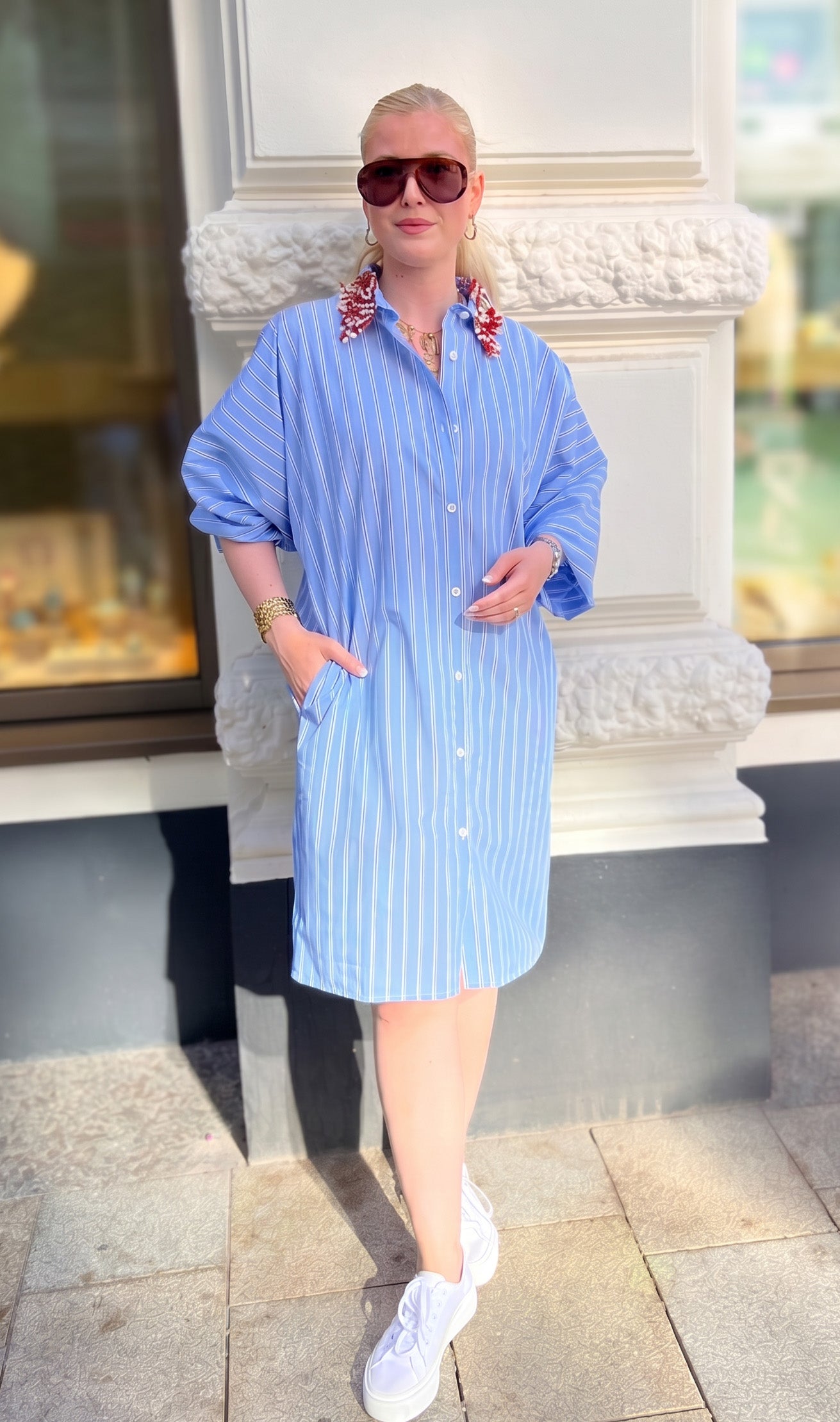 Totale von junger Frau im urbanen Umfeld im Streifenkleid mit Perlenstickerei am Kragen vom Hamburger Modelabel Stegmann Mode