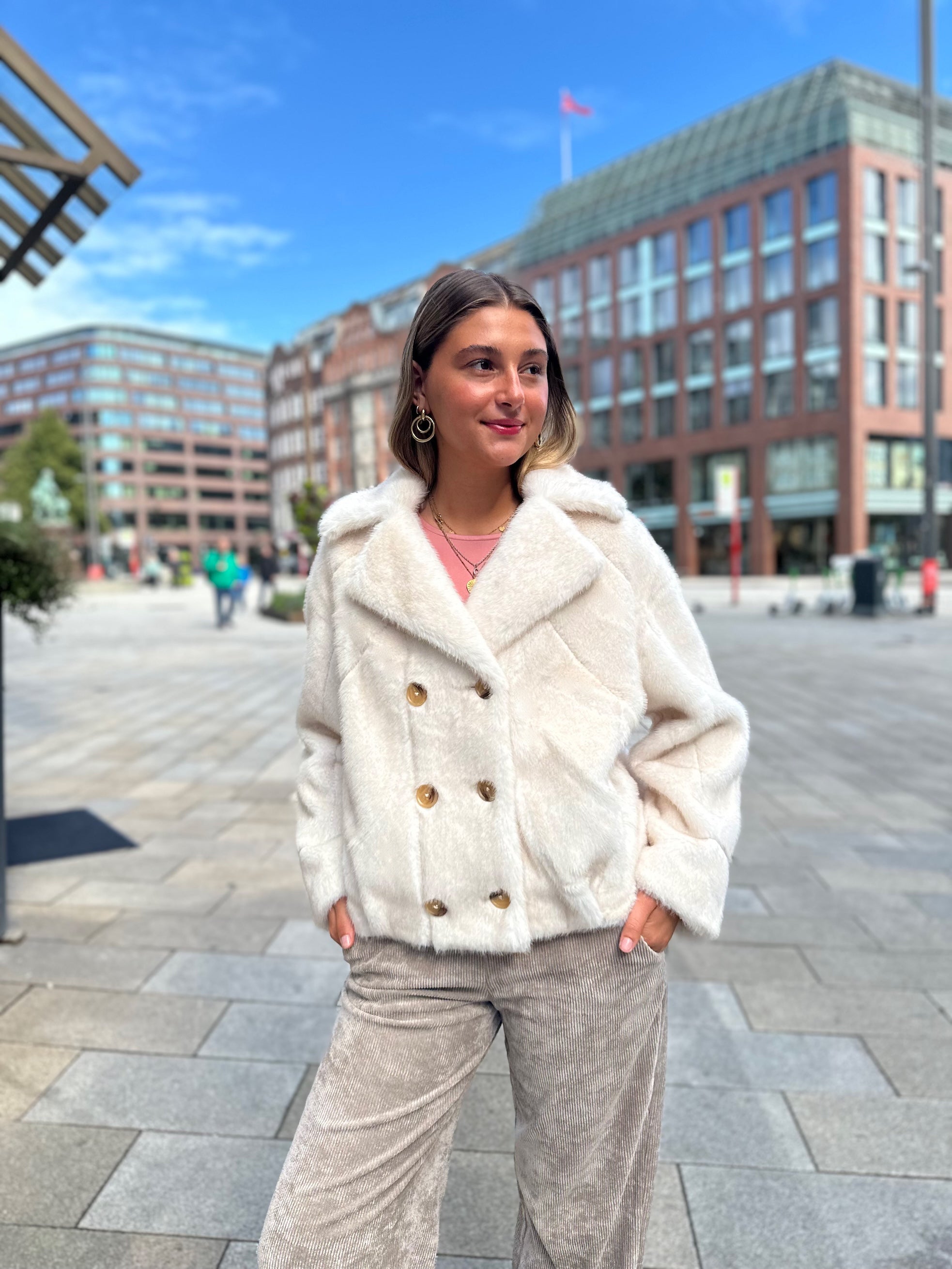 Jung Frau trägt doppelreihigen Funfur Capan in Creme vom Hamburger Modelabel stegmann mode