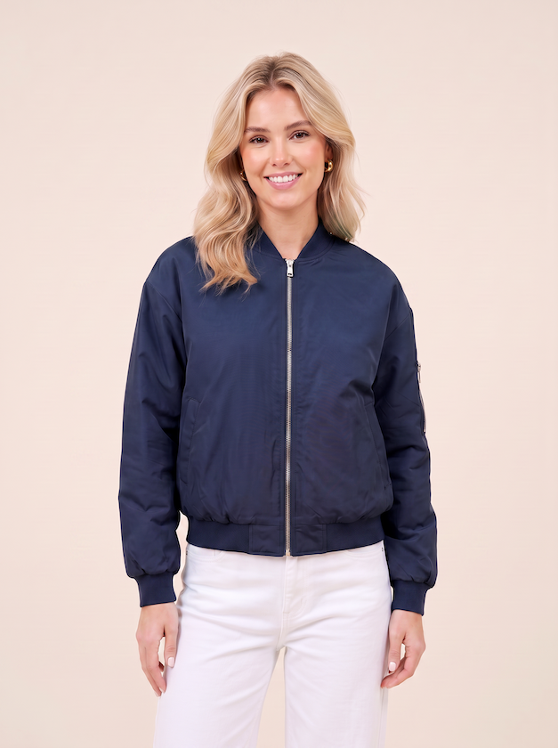 Halbtotale vom KI generiertem Modell in einem hellen Studio in einer Bomberjacke in der Farbe Blau vom Hamburger Modelabel Stegmann Mode