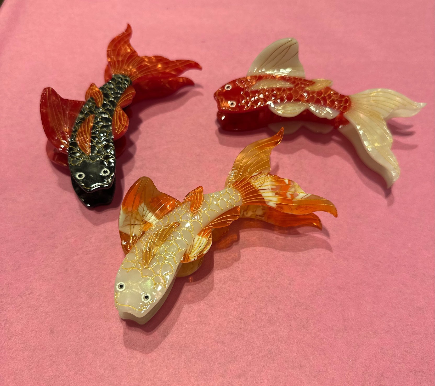 Produktfoto von drei Haarklammern in Koi-Form in drei Farben: schwarz, rot und orange vom Hamburger Modelabel stegmann mode